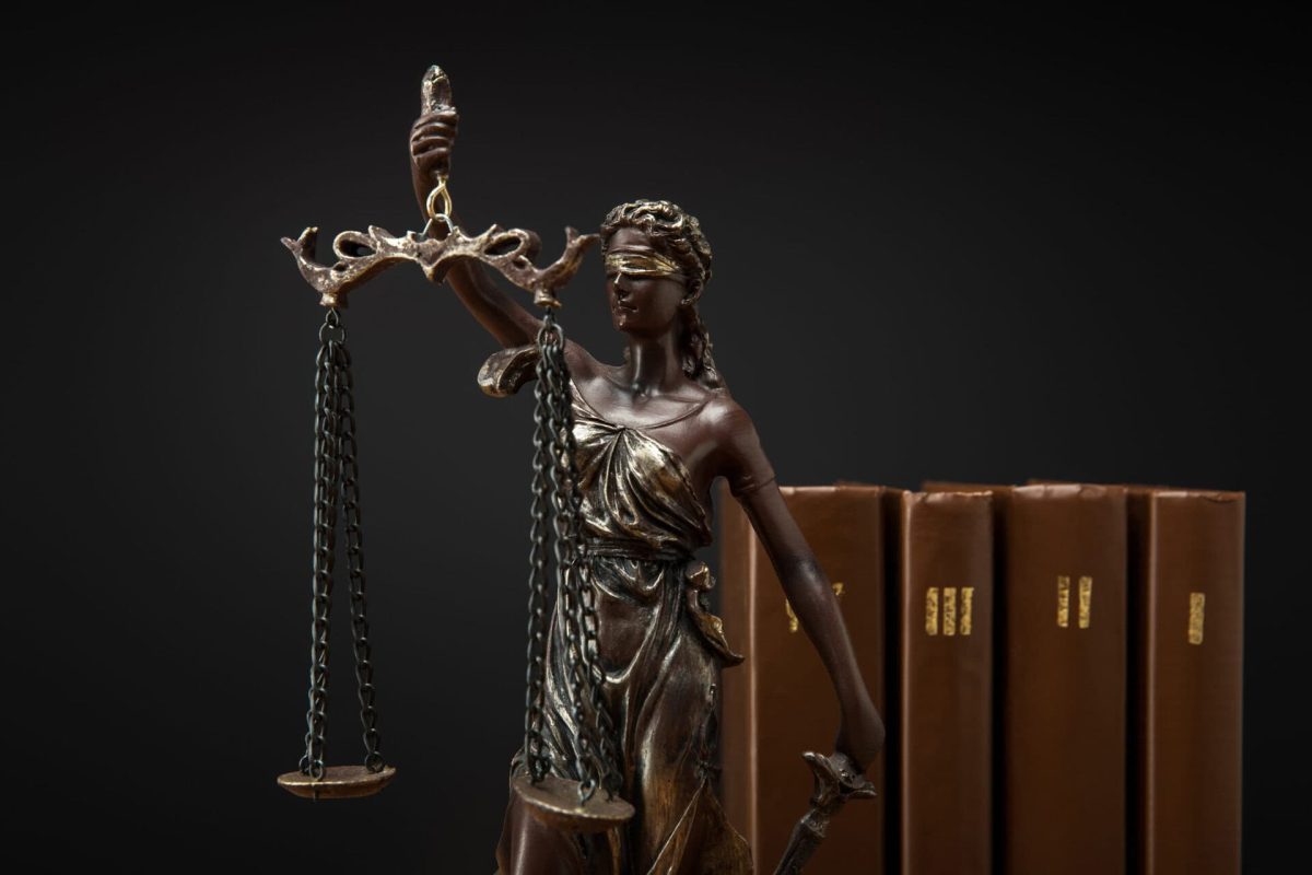 bronze statuette with scales of justice and volumes of brown books isolated on black