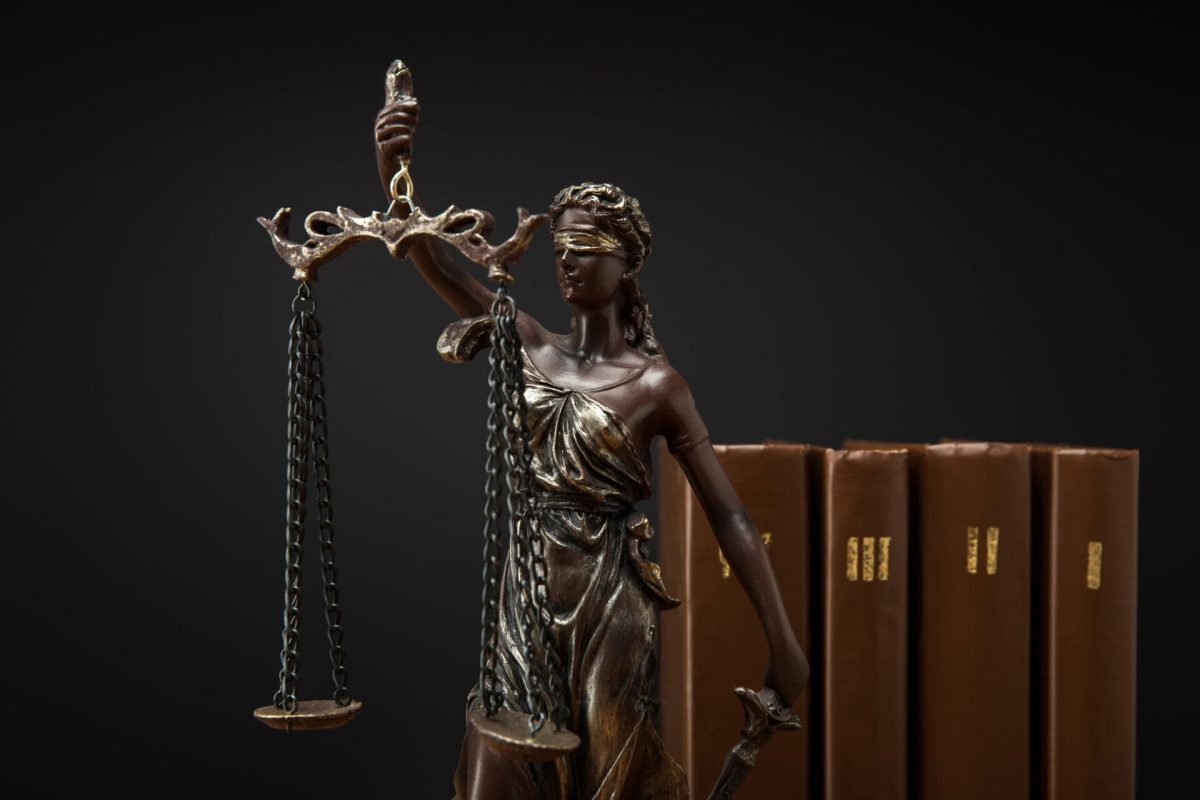 bronze statuette with scales of justice and volumes of brown books isolated on black