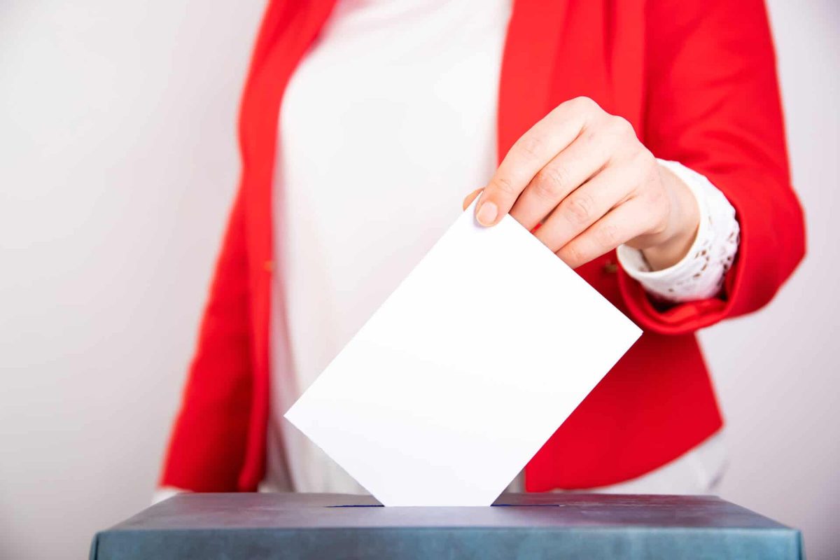 Hand of a voter putting vote in the ballot box. Election concept.